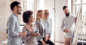 Führungskräfte im Austausch während einer Präsentation – Teamwork und Entwicklung im Rahmen eines INQA-Coachings.