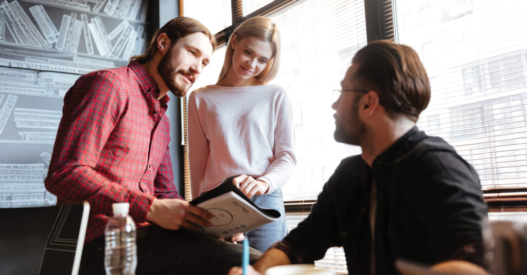 Führungskraft im Gespräch mit zwei Teammitgliedern in einem modernen Büro – richtig delegieren und Aufgaben im Team besprechen.