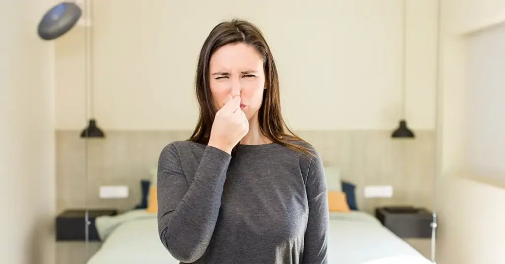 Eine Frau hält sich angeekelt die Nase zu. Sie fragt sich, was sie tun soll, wenn ein Mitarbeiter stinkt