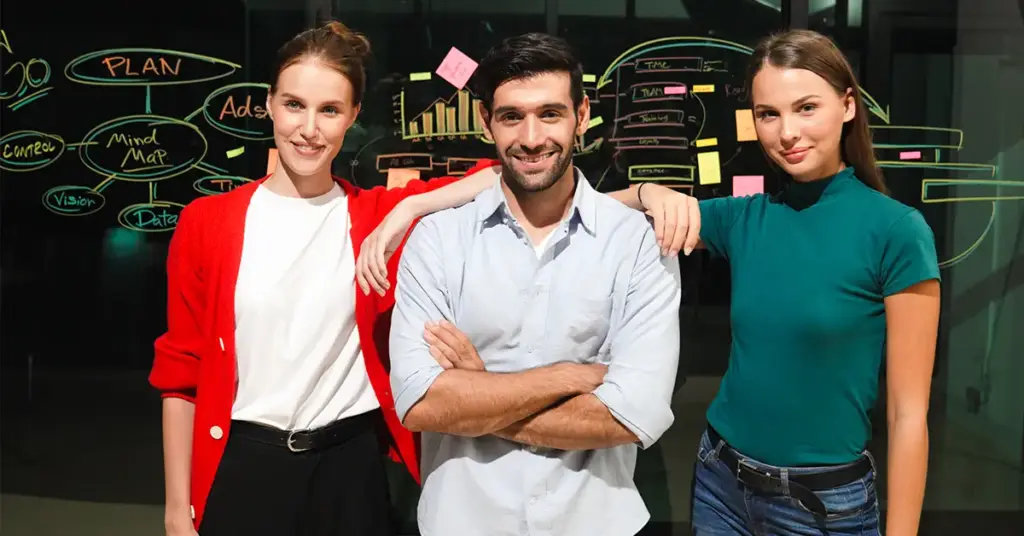 Drei Führungskräfte vor einem Blackboard besprechen die Auswirkungen von Führung auf eine skill-based Organization.