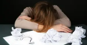 Eine Mitarbeiterin liegt verzweifelt mit dem Kopf auf ihrem Schreibtisch. Ein deutliches Zeichen, dass sie innerlich gekündigt hat.